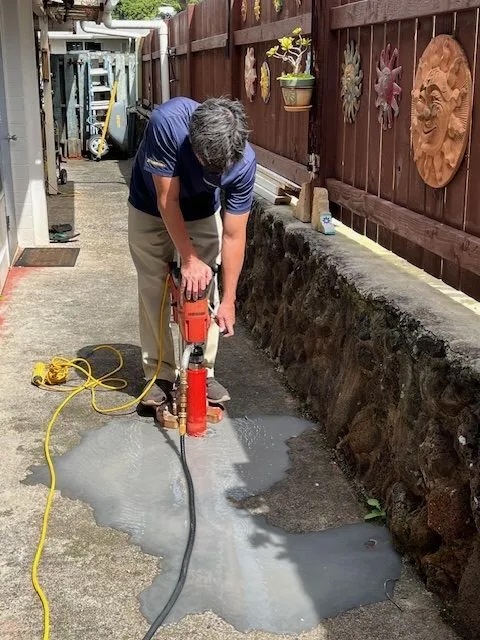 Technician drilling into concrete pathway to install Sentricon® termite bait station.